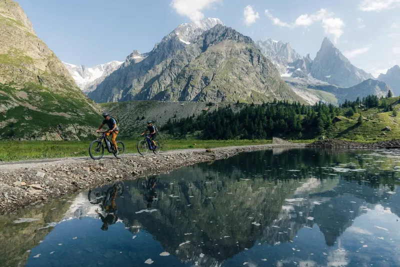 Due rider in bici lungo un lago alpino sotto il Monte Bianco