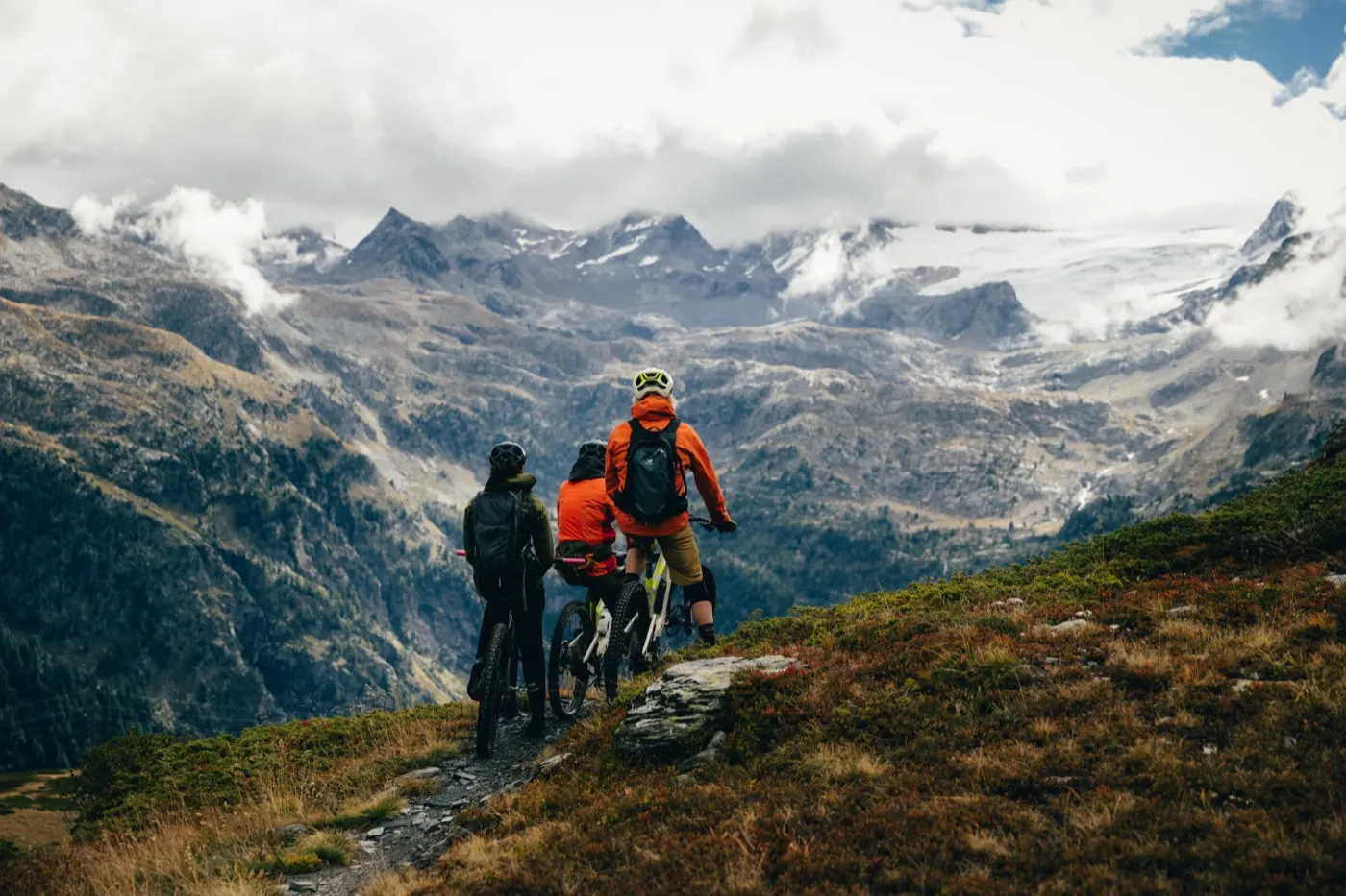Tre persone in bici guardano un ghiacciaio dall'alto di un sentiero